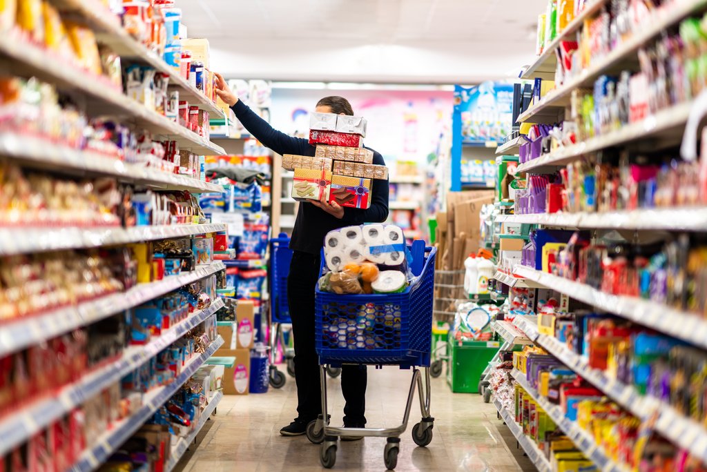 Kundeninspiration: Eine Chance für den Detailhandel | unisg.ch Full shopping cart, customer is stocking vital needs because of global chaos. Shopping with blur supermarket store products, interior background.